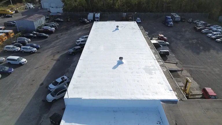 Aerial view of a long commercial building with a white coated flat roof