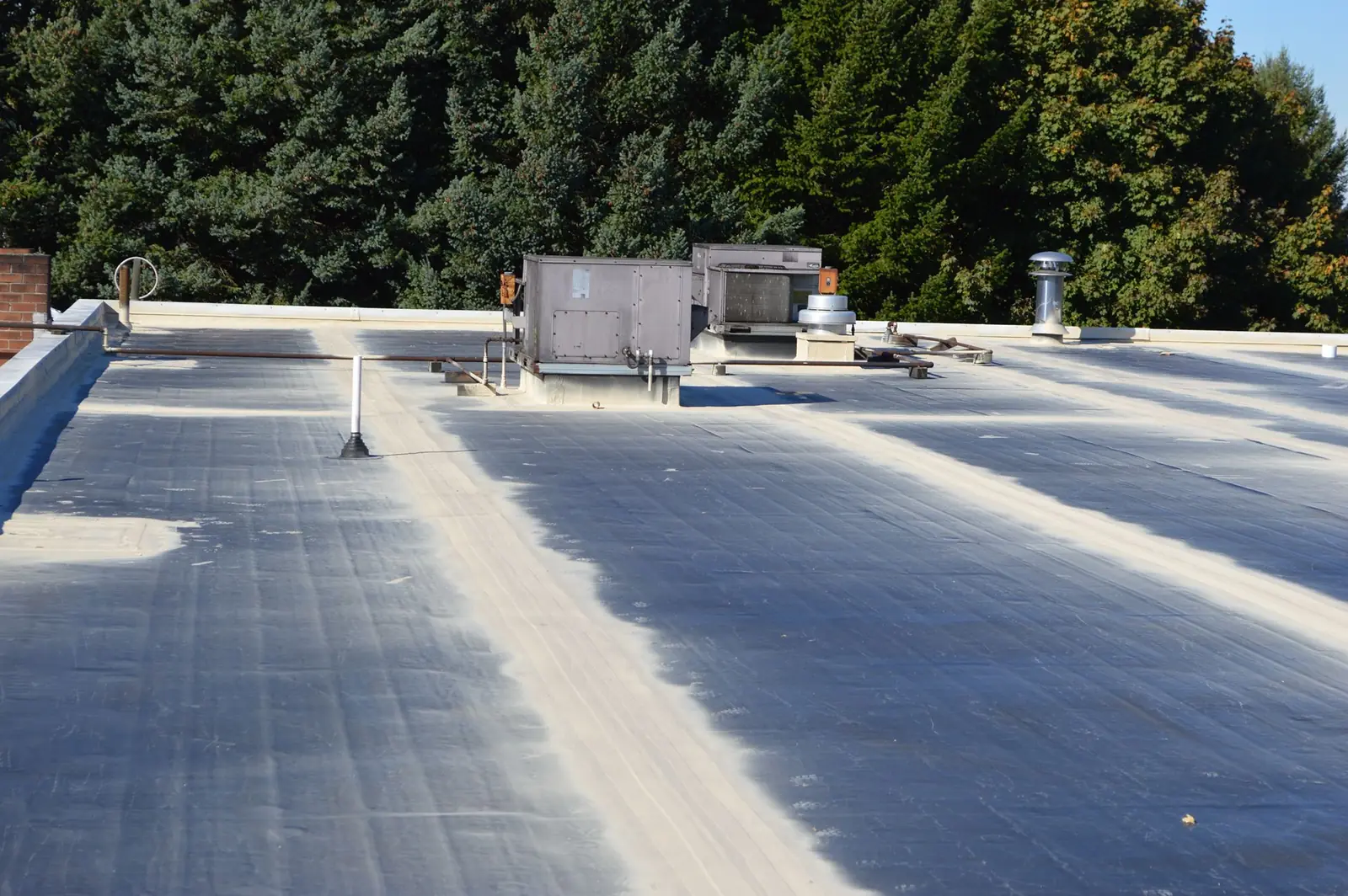 Aged EPDM flat roof with its seams primed and reinforced before coating