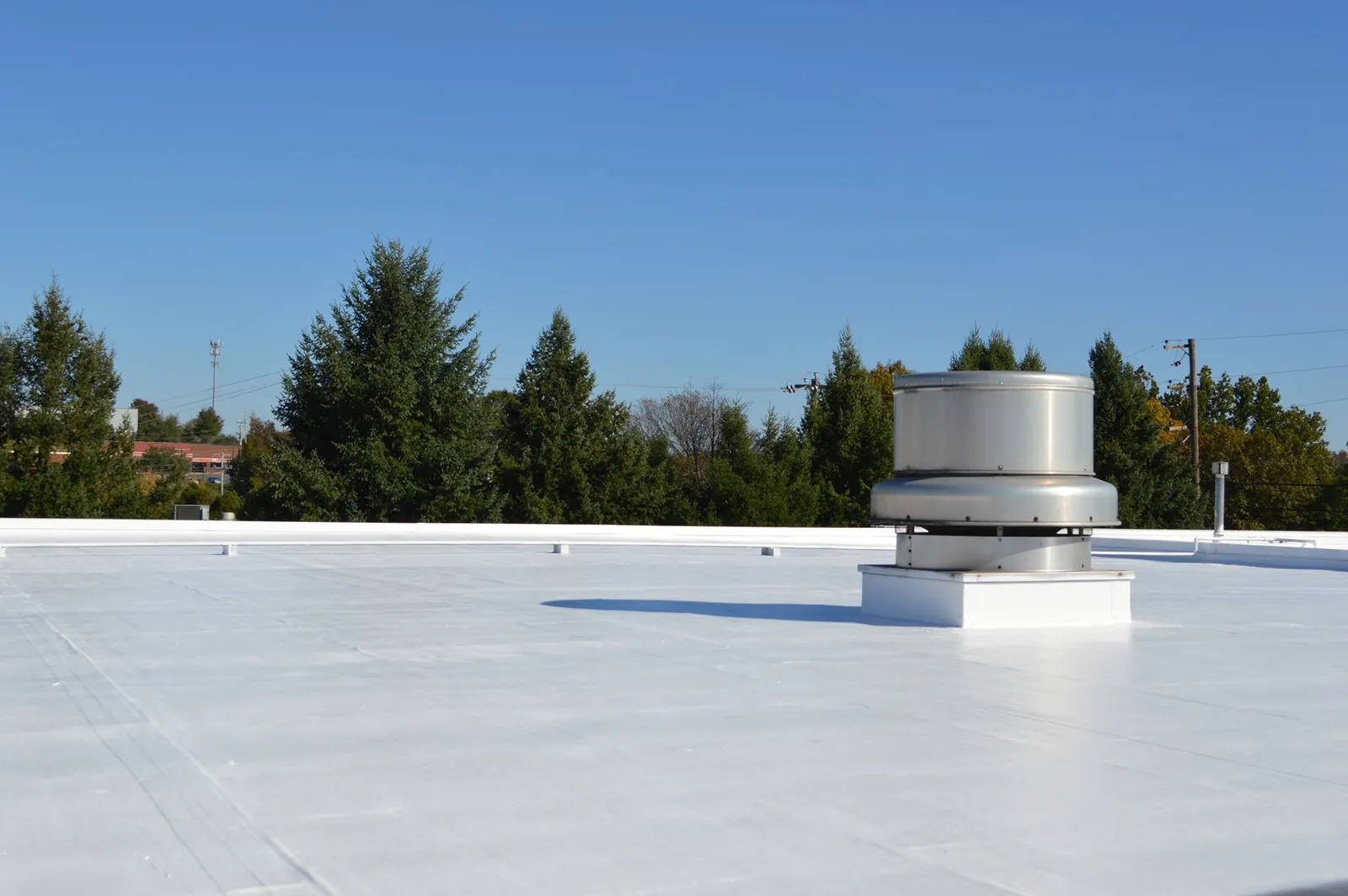 Finished bright white coated flat roof with a sealed vent curb