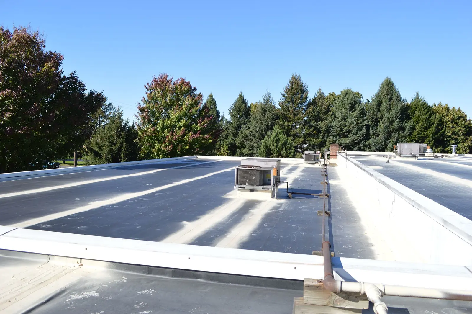 Flat commercial roof with seams prepared around rooftop HVAC units