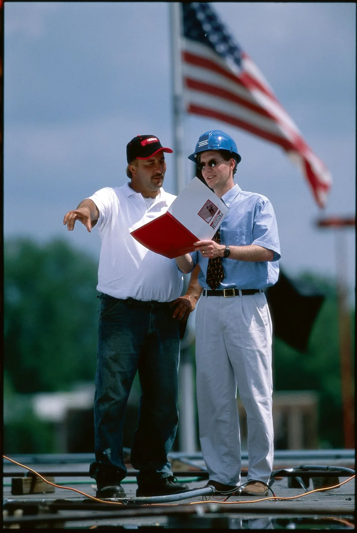 Roofing specialist reviewing a roof inspection report with a building owner