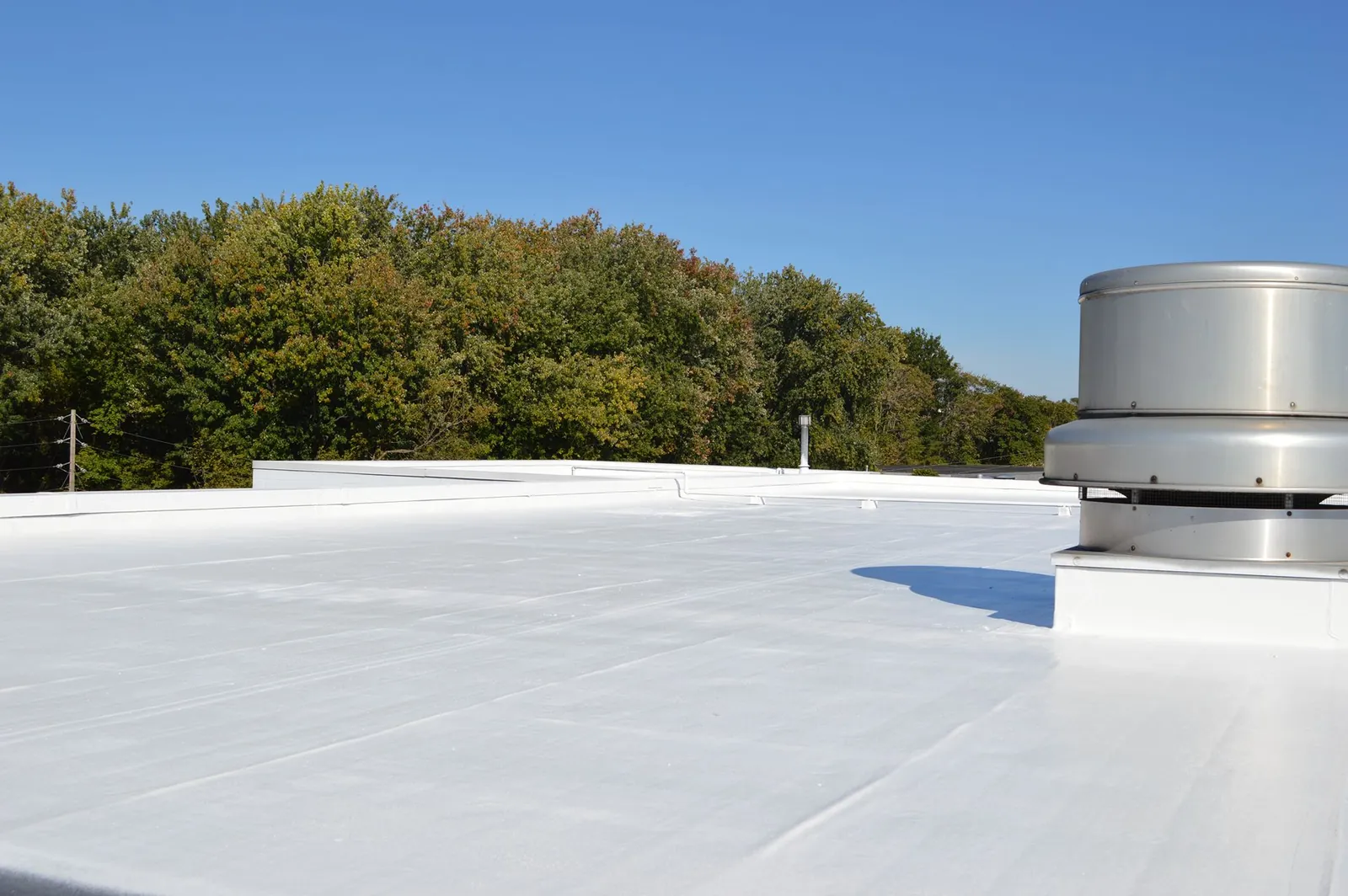 Finished white roof coating around a rooftop exhaust fan