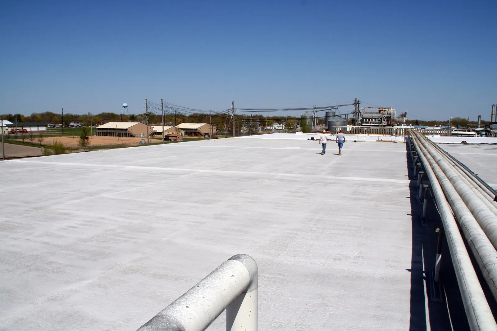 White industrial roof beside an elevated pipe walkway